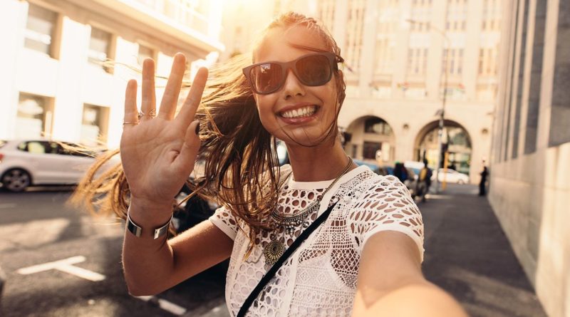 Young woman taking selfie in a street. Tourist posing for a selfie in a street. Vlogger recording content for her travel vlog.