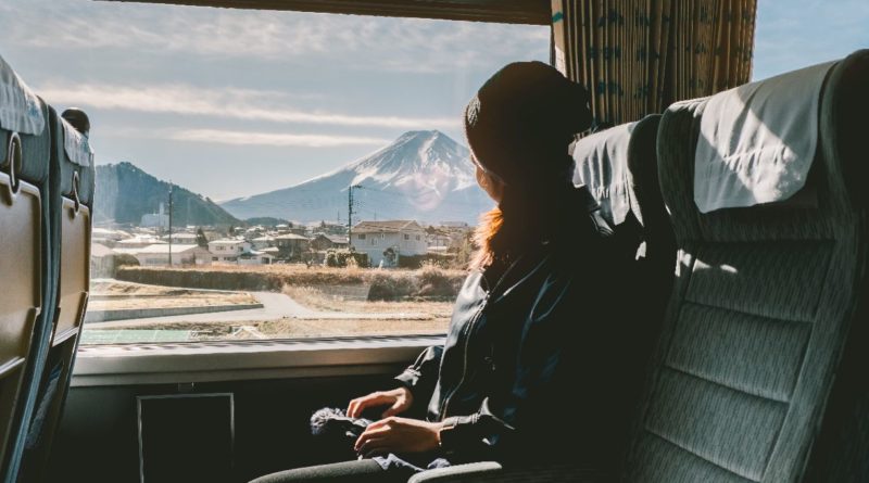 mikro putovanja, putovanja, Enjoying travel. Young pretty woman traveling by the train from sitting near the window and looking mountain Fuji. vintage filter. Travel concept